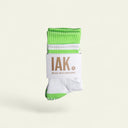IAK Fresh pastel green organic cotton grip socks with full-coverage PVC grip, folded on a beige background